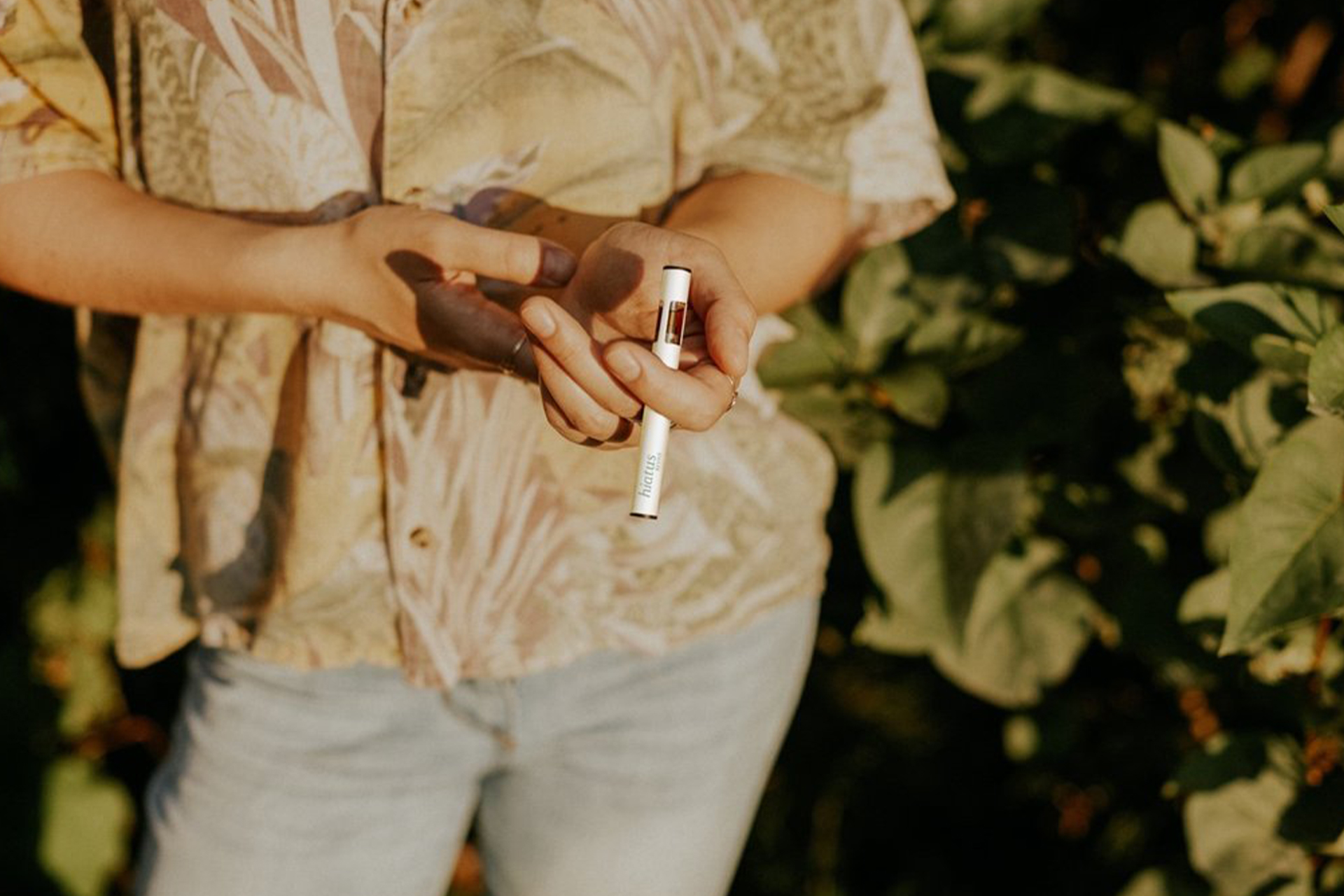 The torso of a person holding a CBD Vape pen.