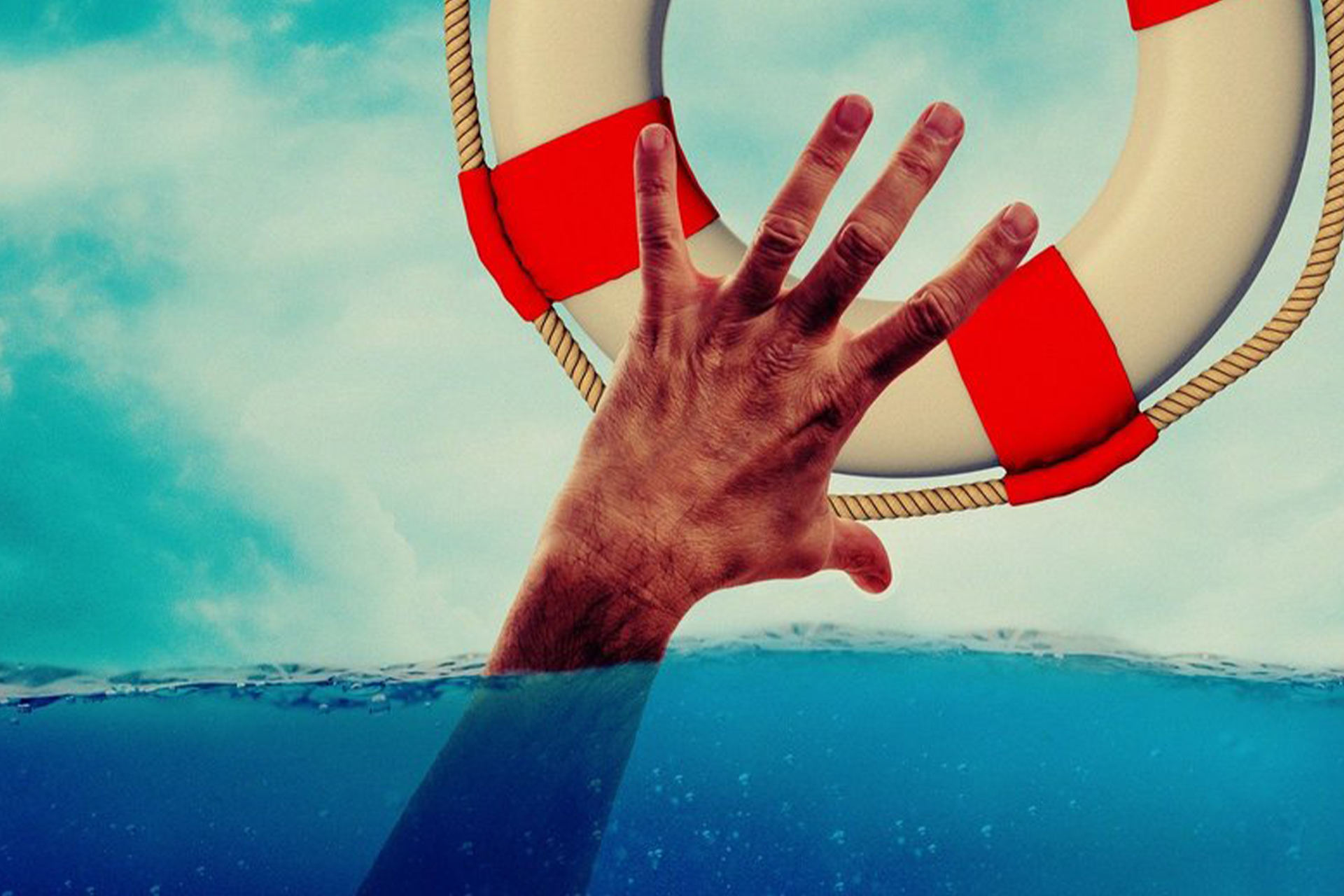 A man's hand reaching out of water for a lifebuoy.