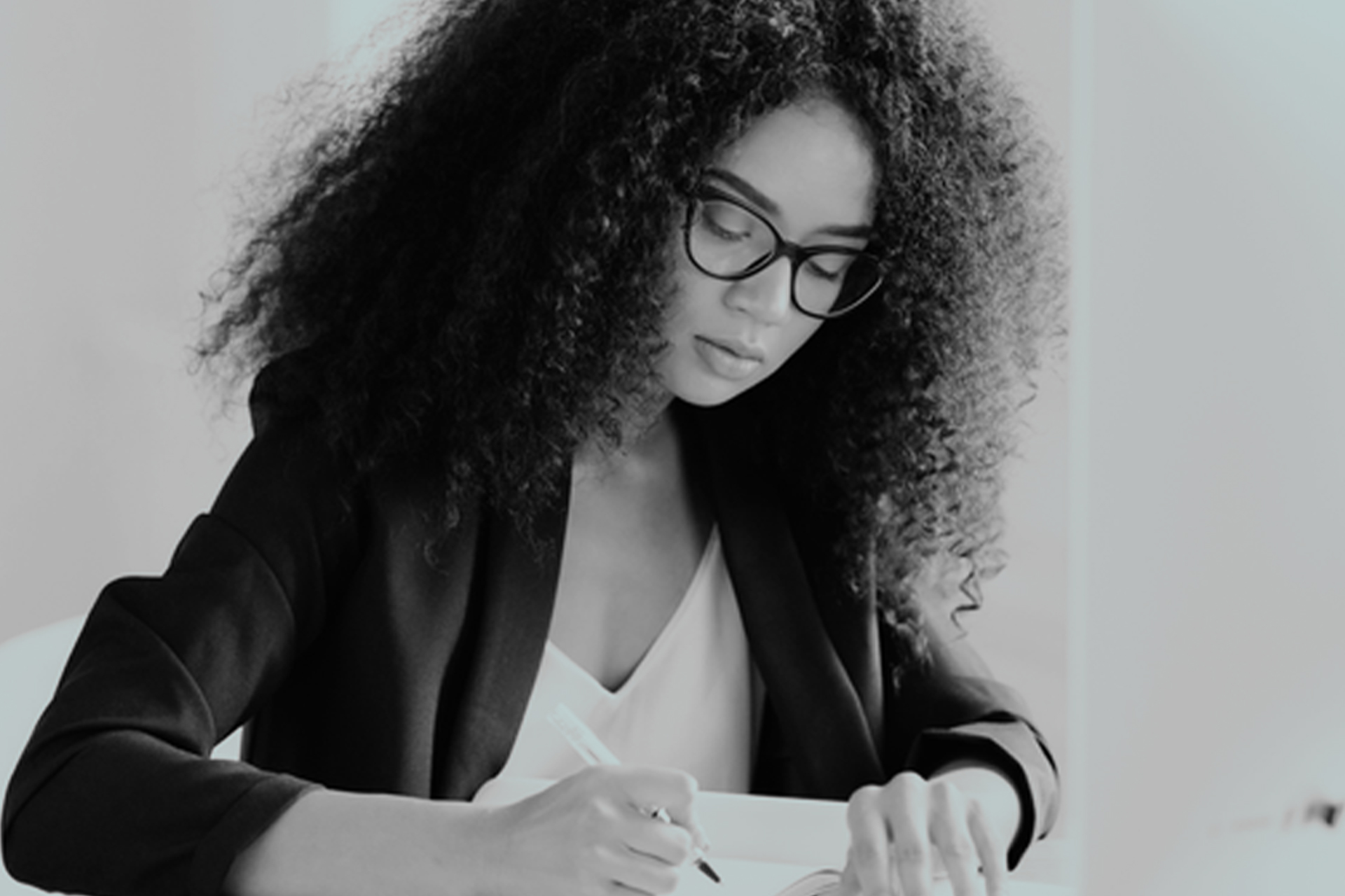 A black and white picture of a young lady writing.