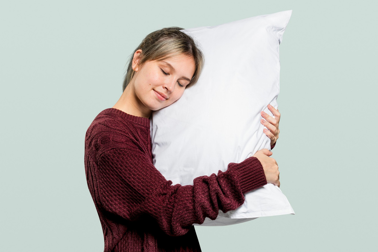 Standing young woman with her eyes closed and head resting on a pillow.